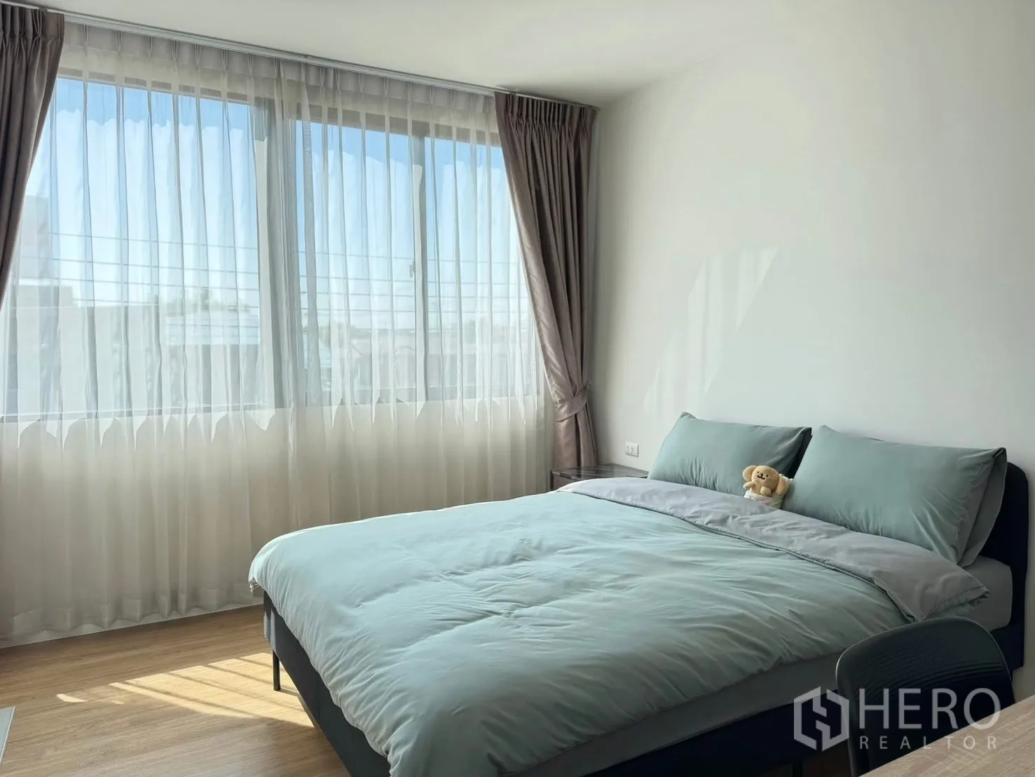 Townhouse for rent in Saphan Sung, Bangkok - Sunlit bedroom with large corner windows and sheer curtains.