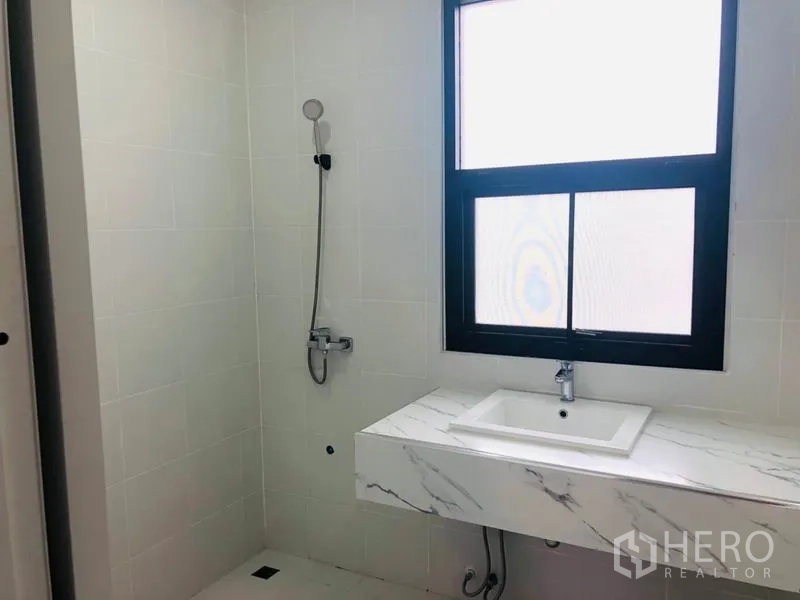 สำนักงานที่บ้าน ให้เช่าในKhlong Toei, Bangkok - ห้องน้ำกระเบื้องสีขาว พร้อมฝักบัวอาบน้ำและเคาน์เตอร์ลายหินอ่อน ใต้หน้าต่างฝ้า