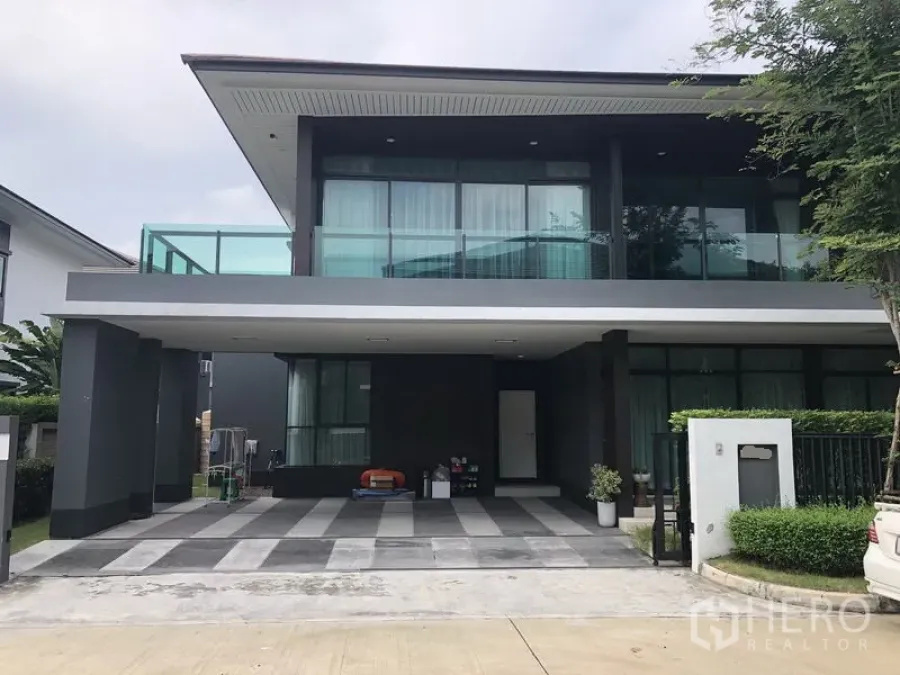 Detached House for rent or sale in Bang Kapi, Bangkok - Modern two-storey detached house with glass balcony and wide covered carport in a gated estate.