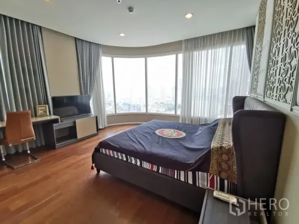Condominium for rent in Bang Kho Laem, Bangkok - Master bedroom with curved floor-to-ceiling windows, a desk and skyline views.