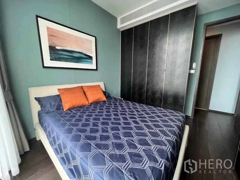 Condominium for rent in Watthana, Bangkok - Second bedroom with double bed, artwork, orange accent pillows and floor-to-ceiling wardrobe.
