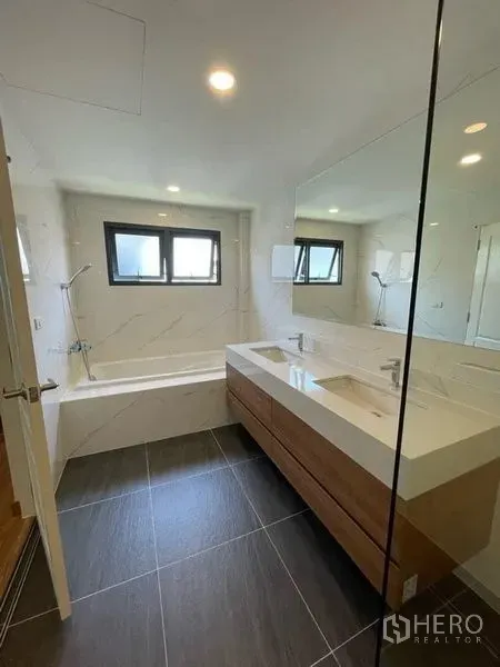 Detached House for rent in Don Mueang, Bangkok - Bright bathroom with bathtub, double vanity and large mirror under twin windows.