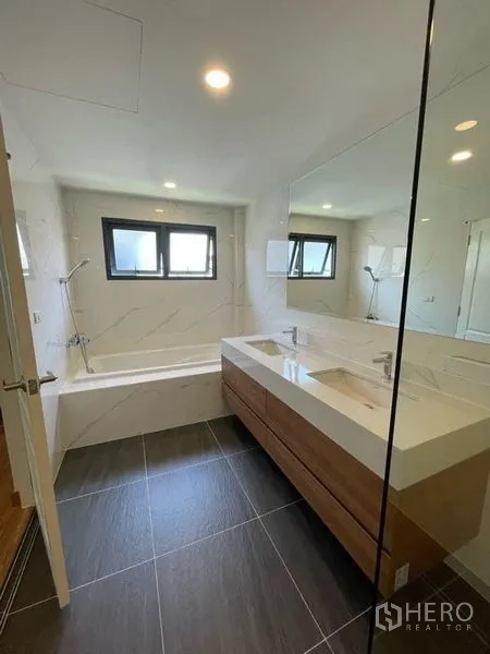 Detached House for rent in Don Mueang, Bangkok - Bright bathroom with bathtub, double vanity and large mirror under twin windows.
