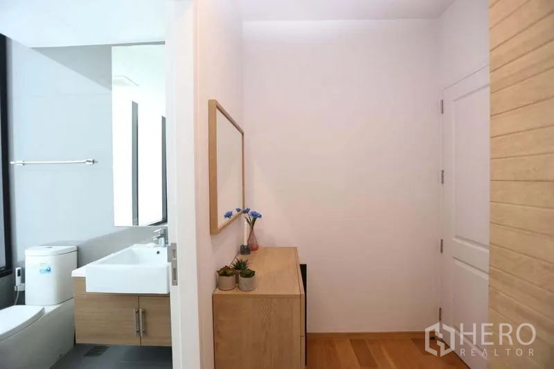 Condominium for sale in Bang Rak, Bangkok - Hallway vanity area leading to bathroom with large mirror and storage cabinet.