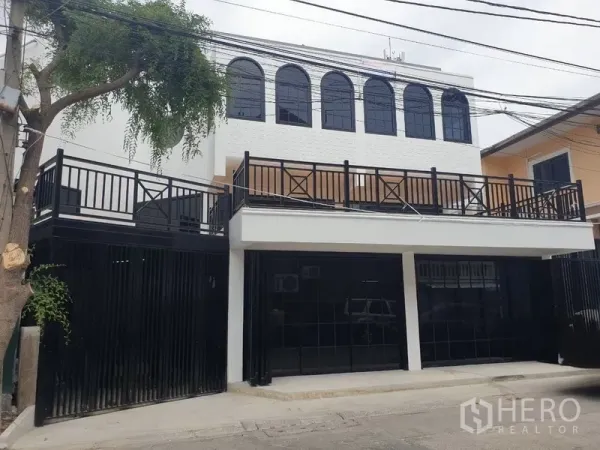 带办公室的家 出租或出售在Bang Na, Bangkok - 现代白色两层家庭式办公外立面，黑色大门与拱形窗。