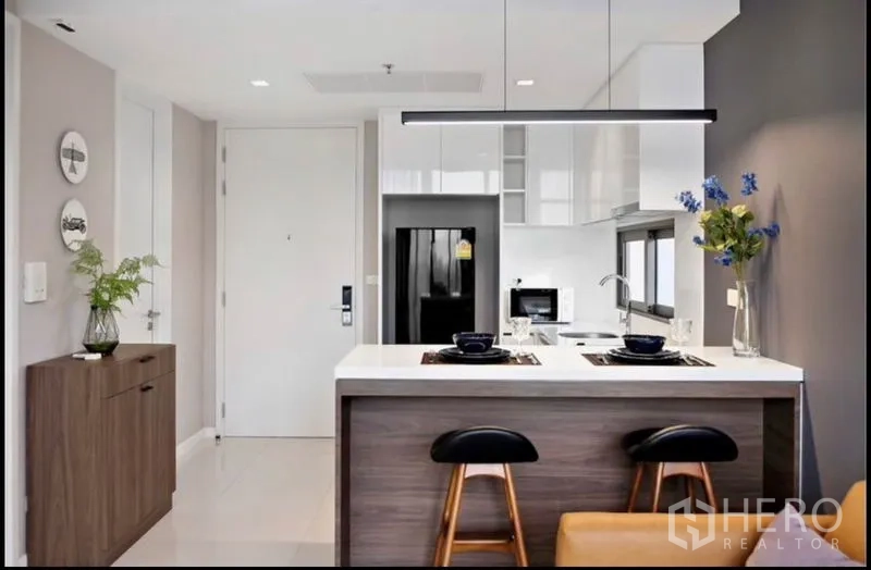 Condominium for rent in Bang Rak, Bangkok - Kitchen island with two barstools and linear pendant light in a modern condo.