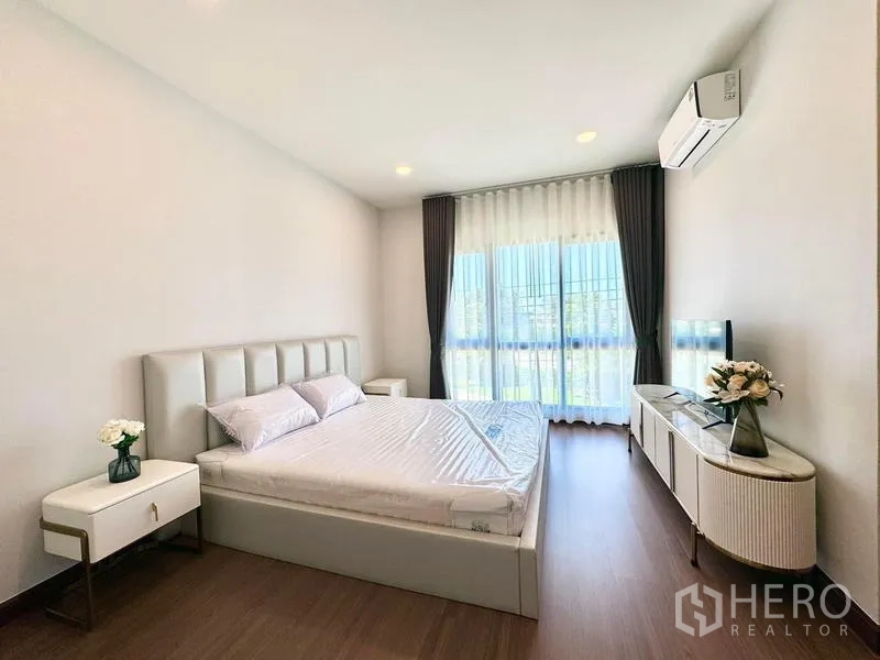 Detached House for rent or sale in Bang Phli, Samut Prakan - Bright bedroom with a king bed, floor-to-ceiling window, TV console, and air conditioning.