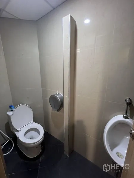 办公空间 出租 - 办公室卫生间配坐便与小便斗，深色地砖，方便员工使用。