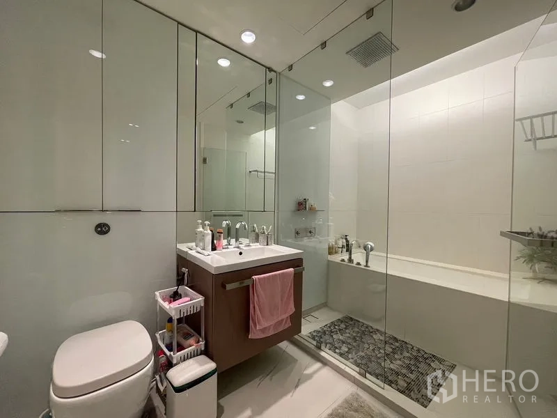 Condominium for rent in Pathum Wan, Bangkok - Modern bathroom with glass-enclosed shower, vanity and separate soaking tub.