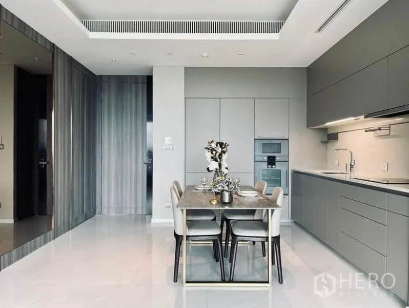 Condominium for rent in Pathum Wan, Bangkok - Modern fitted kitchen with integrated appliances and a four-seat dining table in neutral tones.