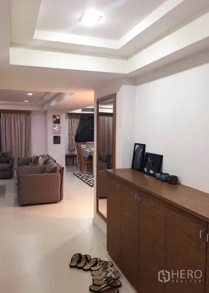 Condominium for rent or sale in Watthana, Bangkok - Entry hallway with wooden cabinet and mirror leading to a bright lounge and dining area with curtains.