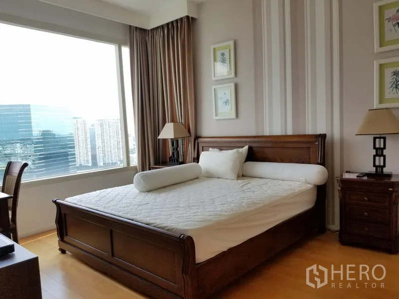 Condominium for rent in Chatuchak, Bangkok - Spacious master bedroom with a classic wooden bed and a large window overlooking the Bangkok skyline.