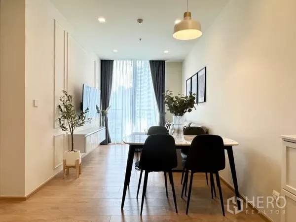 公寓 出租在Watthana, Bangkok - 餐区设四把黑色椅，面向落地窗与城市景观，旁边为电视柜。