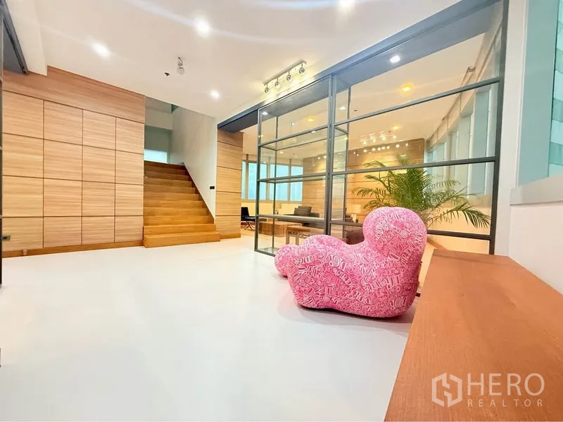 คอนโด ให้เช่าหรือขายในKhlong Toei, Bangkok - พื้นที่เปิดโล่ง ผนังกระจกและเก้าอี้สีชมพูเชื่อมสู่ห้องนั่งเล่น มีไฟฝังและต้นไม้