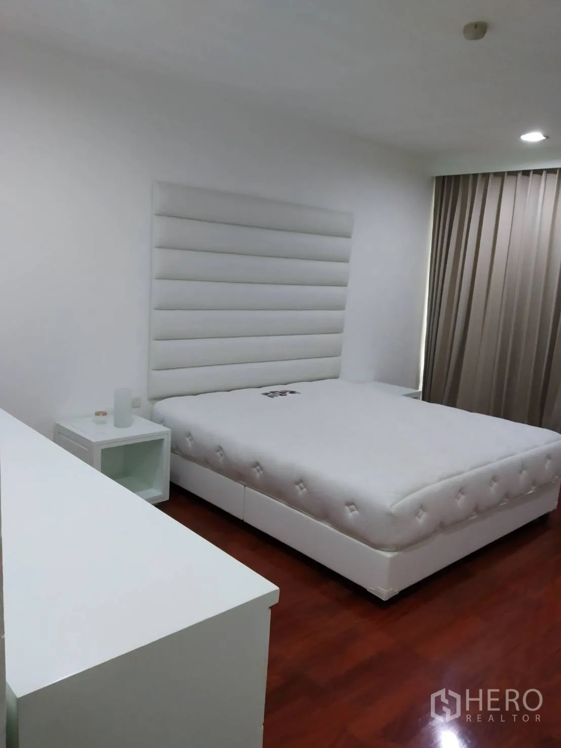Condominium for rent in Pathum Wan, Bangkok - Second bedroom with white bed, bedside tables and blackout curtains.