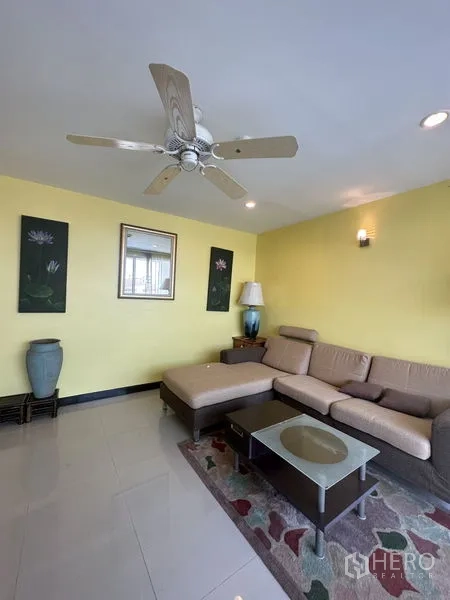 Condominium for sale in Watthana, Bangkok - Living room corner featuring sectional sofa, coffee table, wall art and ceiling fan.