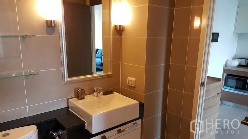 Condominium for rent in Sathon, Bangkok - Modern bathroom with square basin, mirror, shelving and tiled walls.