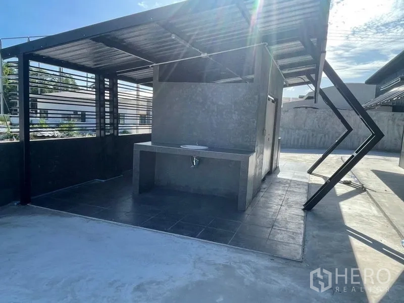 Warehouse for rent in Ban Bueng, Chon Buri - Outdoor wash and utility area with sink under a metal roof next to the warehouse.