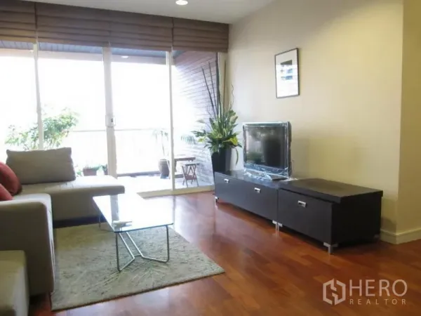 คอนโด ให้เช่าในKhlong Toei, Bangkok - ห้องนั่งเล่นสว่าง พร้อมชั้นวางทีวีและประตูกระจกบานเลื่อนออกระเบียงที่มีต้นไม้