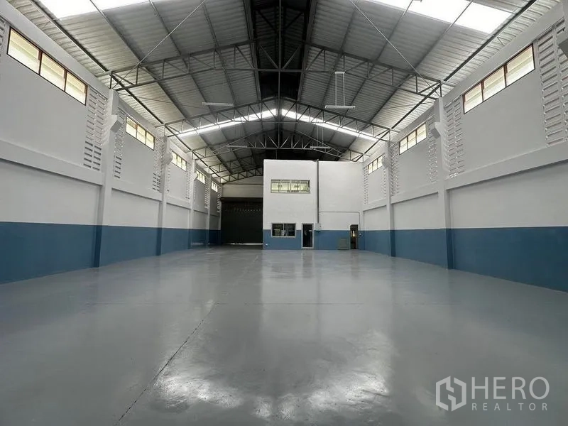 工厂 出租在Pathum Thani - 仓库内部朝向办公室箱体与大型卷帘门。