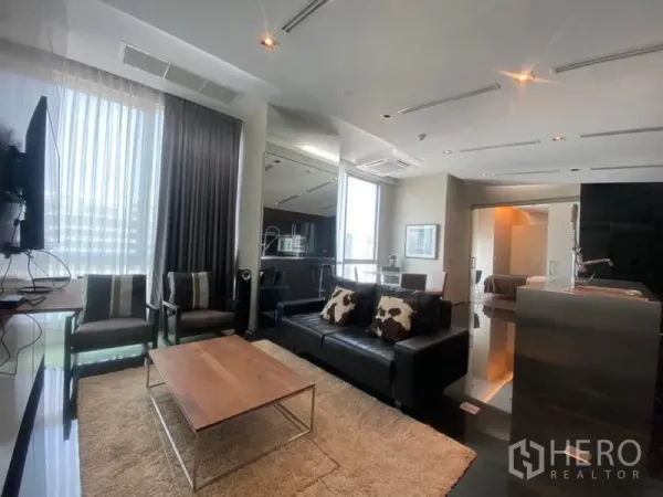 Condominium for rent in Sathon, Bangkok - Open-plan living room with leather sofa, armchairs, coffee table and floor-to-ceiling windows at Sky Villas Sathorn.