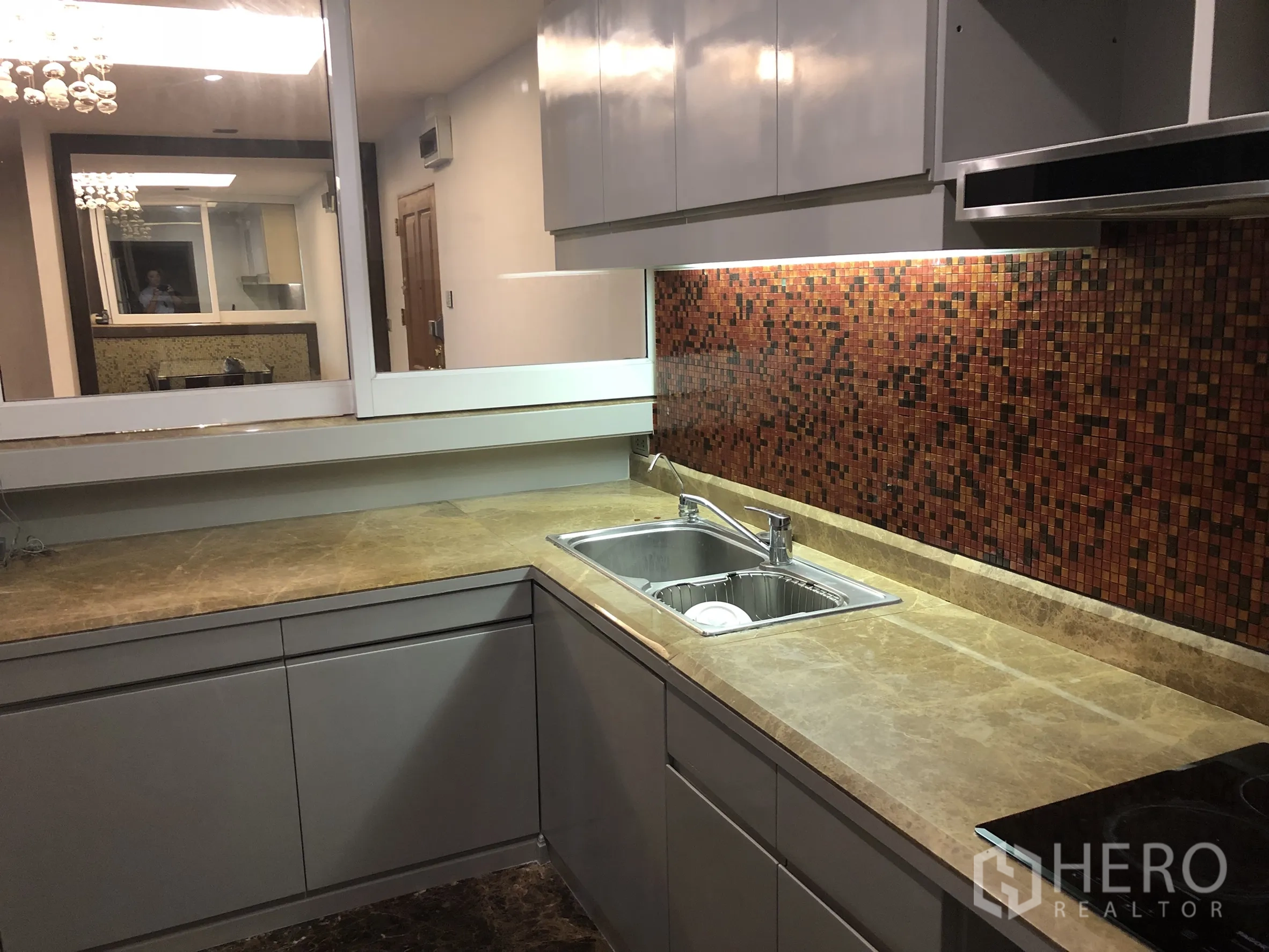 公寓 出租在Sathon, Bangkok - L形厨房，石材台面、双水槽与暖色马赛克防溅板。