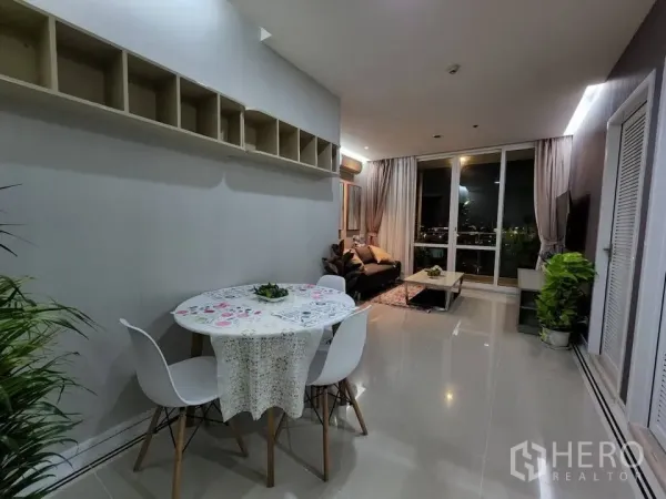 Condominium for rent in Huai Khwang, Bangkok - Open-plan dining space with round table leading to living room and balcony.