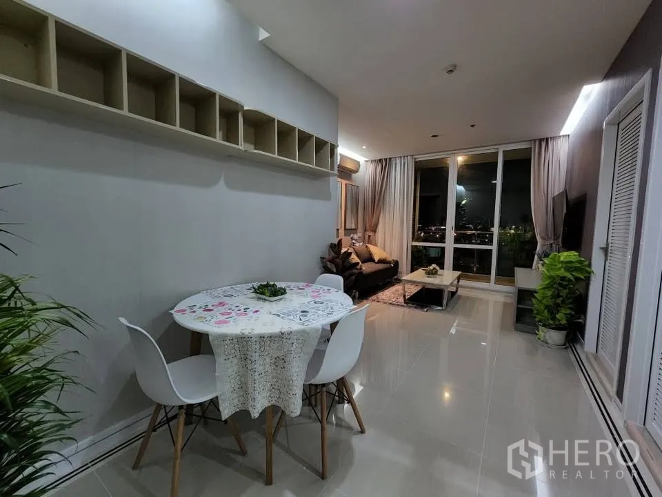 Condominium for rent in Huai Khwang, Bangkok - Open-plan dining space with round table leading to living room and balcony.