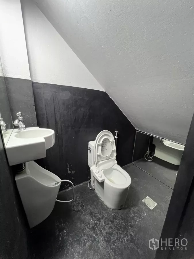 店屋 出租在Watthana, Bangkok - 楼梯下的小卫生间，坐便器、洗手盆与镜子。