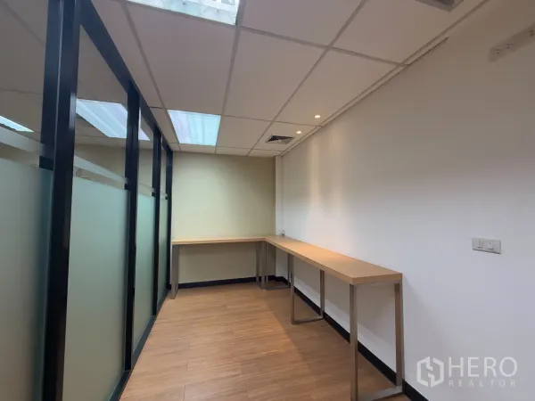 办公空间 出租 - 狭长工作间，长条操作台与磨砂玻璃隔断、木纹地面。