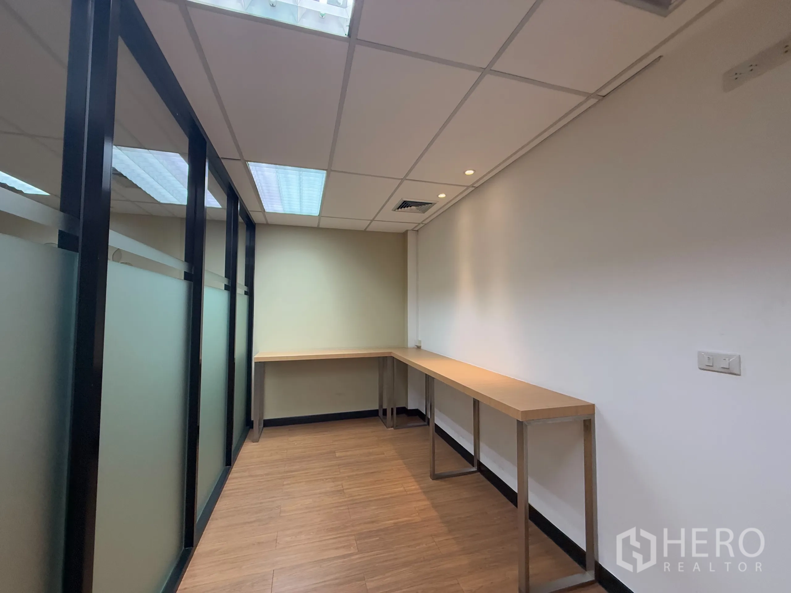 办公空间 出租 - 狭长工作间，长条操作台与磨砂玻璃隔断、木纹地面。