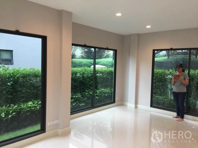 Detached House for sale in Pak Kret, Nonthaburi - Light-filled living area with large corner windows and garden view