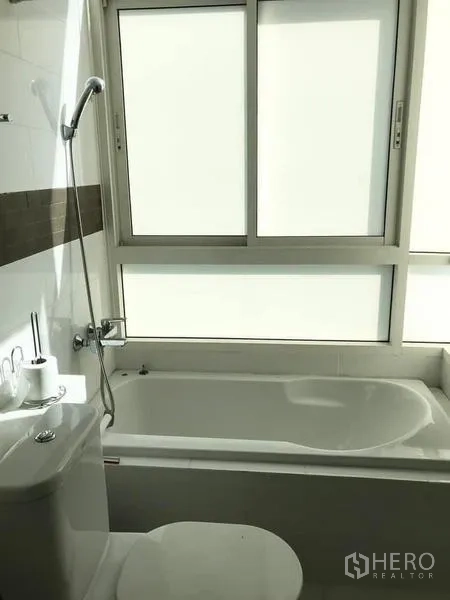 Condominium for rent or sale - Bathroom with bathtub under frosted window and handheld shower.