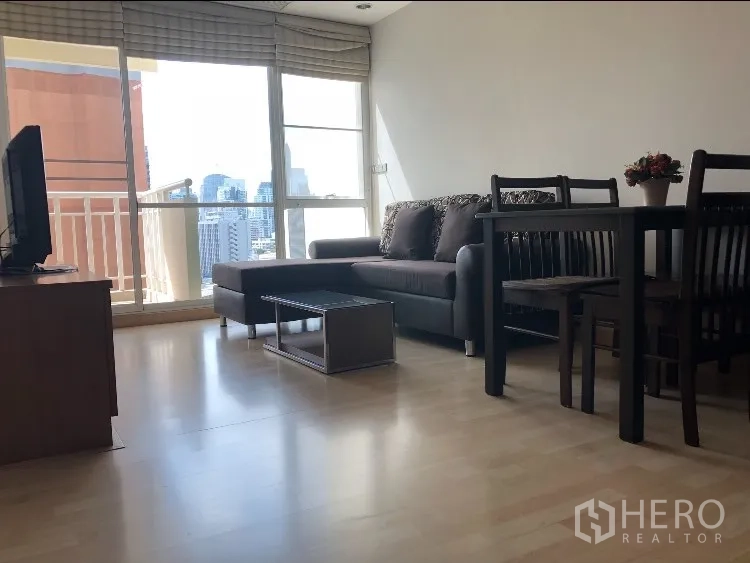 公寓 出租在Watthana, Bangkok - 客餐厅一体，转角沙发、电视与眺望城市的阳台。