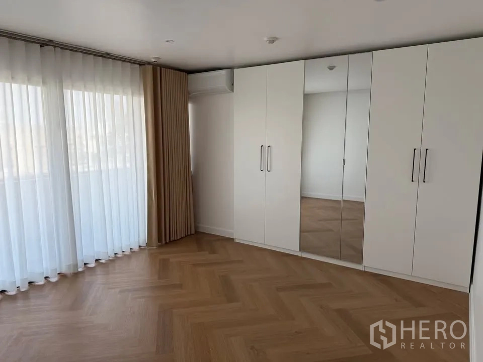 Condominium for rent in Watthana, Bangkok - Bedroom with floor-to-ceiling curtains and mirrored wardrobes.