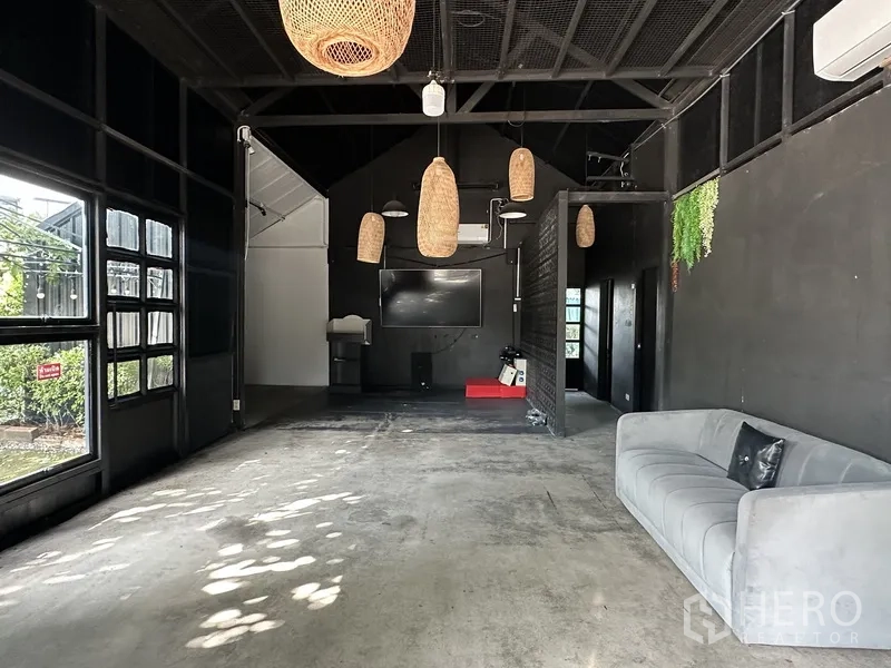 Retail Space for rent in Phra Khanong, Bangkok - Open retail interior with grey sofa, pendant lights, TV and concrete floor.