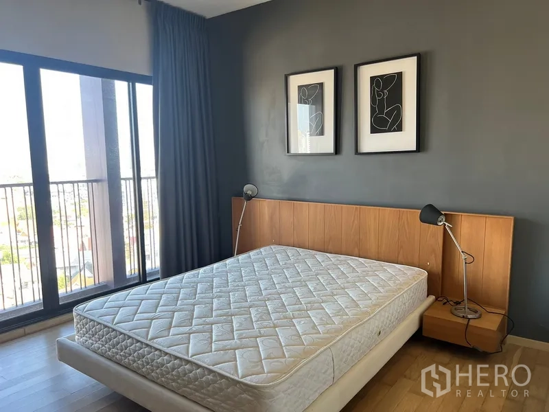 Condominium for rent or sale in Watthana, Bangkok - Bedroom with large windows and balcony, wood headboard and twin bedside lamps