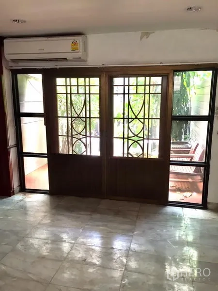 ทาวน์เฮาส์ ให้เช่าในWatthana, Bangkok - พื้นที่ชั้นล่างพื้นหินอ่อน ประตูบานเลื่อนกรอบเหล็กลายเปิดสู่เฉลียงที่มีต้นไม้