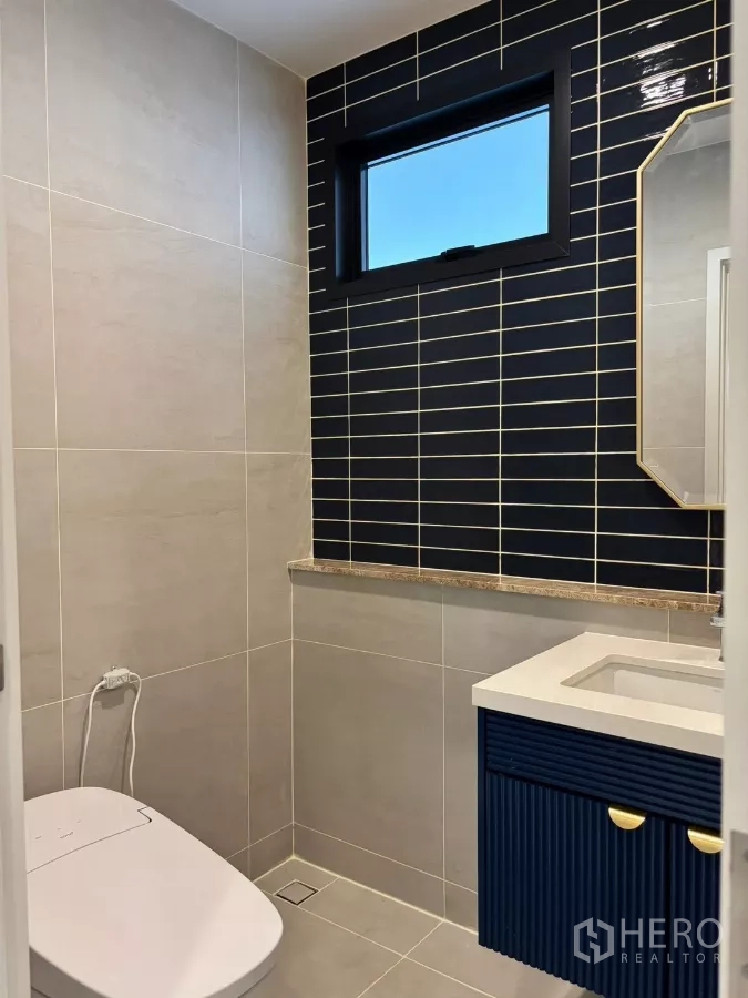 独立式住宅 出租在Bang Phli, Samut Prakan - 客用卫浴，海军蓝亮面瓷砖点缀与现代洁具。