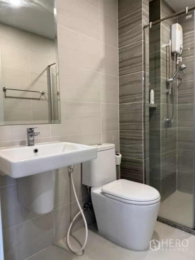 คอนโด ให้เช่าในKhlong Toei, Bangkok - ห้องน้ำโทนเทาพร้อมฉากกั้นอาบน้ำกระจก อ่างล้างหน้า และโถสุขภัณฑ์