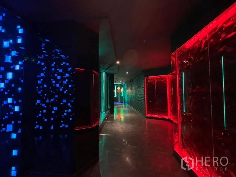 零售空间 出租在Ratchathewi, Bangkok - 走廊两侧为红蓝发光装饰板与反射墙面。