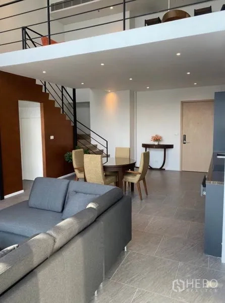 公寓 出租在Bang Rak, Bangkok - 开放式起居区，圆形餐桌，夹层与设计感楼梯。