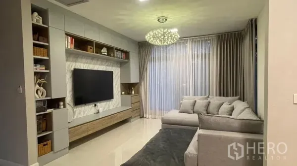 Detached House for rent in Bang Phli, Samut Prakan - Bright living room with built-in TV wall, L-shaped sofa and chandelier