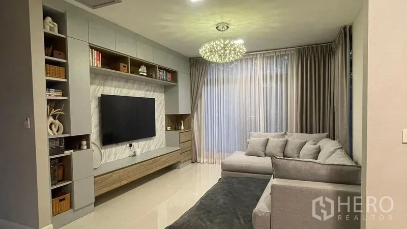 Detached House for rent in Bang Phli, Samut Prakan - Bright living room with built-in TV wall, L-shaped sofa and chandelier