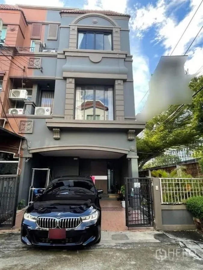 ทาวน์เฮาส์ ขายในBang Phli, Samut Prakan - ด้านหน้าทาวน์เฮ้าส์ 3 ชั้น พร้อมรั้วและที่จอดรถมีหลังคา.