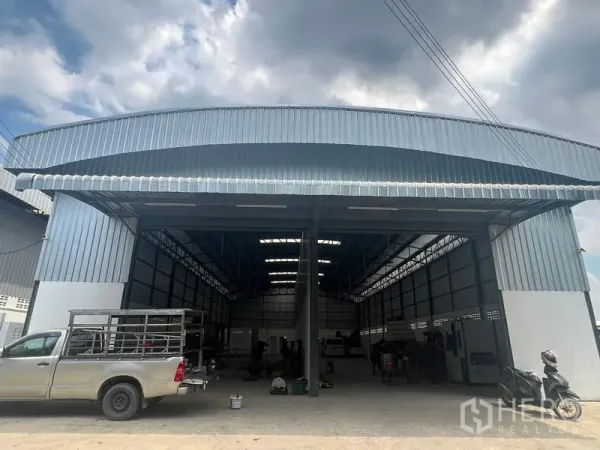 货栈 出租在Khlong Sam Wa, Bangkok - 工业仓库正立面宽阔，金属屋檐遮雨，皮卡与货车可直接驶入装卸。