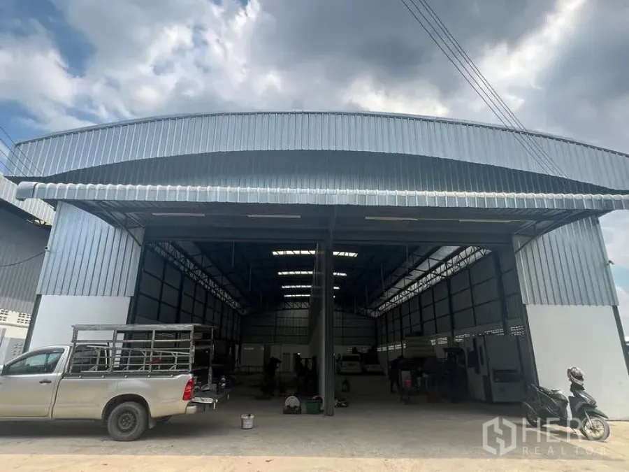 货栈 出租在Khlong Sam Wa, Bangkok - 工业仓库正立面宽阔，金属屋檐遮雨，皮卡与货车可直接驶入装卸。