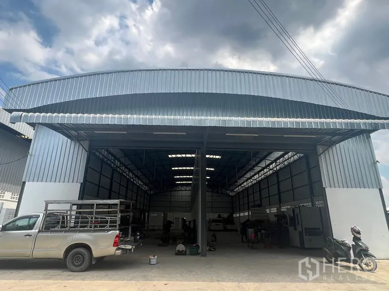 货栈 出租在Khlong Sam Wa, Bangkok - 工业仓库正立面宽阔，金属屋檐遮雨，皮卡与货车可直接驶入装卸。