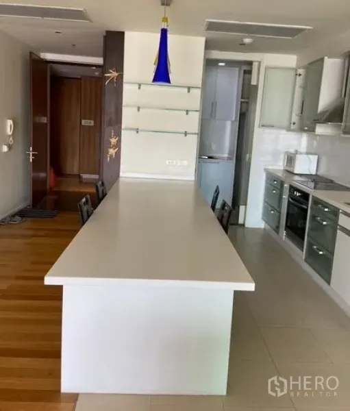 公寓 出租在Khlong Toei, Bangkok - 现代厨房配长形白色中岛、吊灯与内置家电。