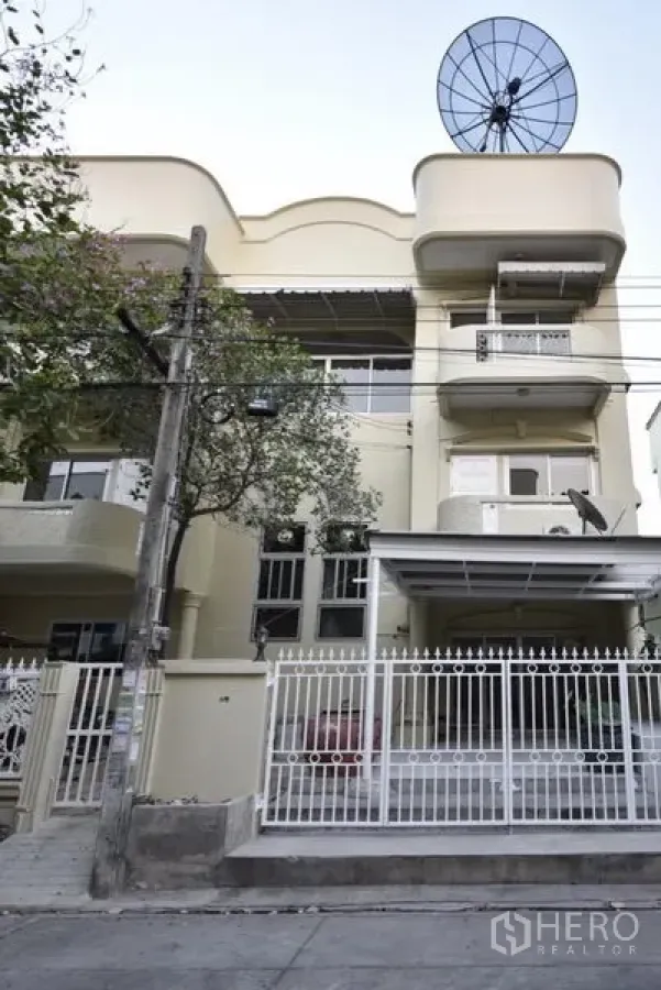 Townhouse for rent in Wang Thonglang, Bangkok - Three-storey townhouse exterior with balconies, gated carport and satellite dish in Bangkok.